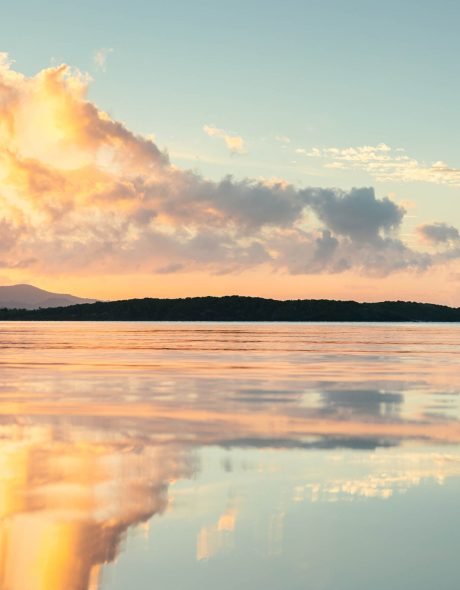 Seven seas beach with calm water reflecting the sky during the g